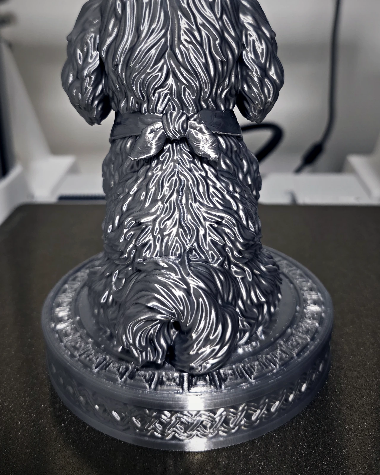 Costas da escultura do cachorrinho, com uma árvore entalhada