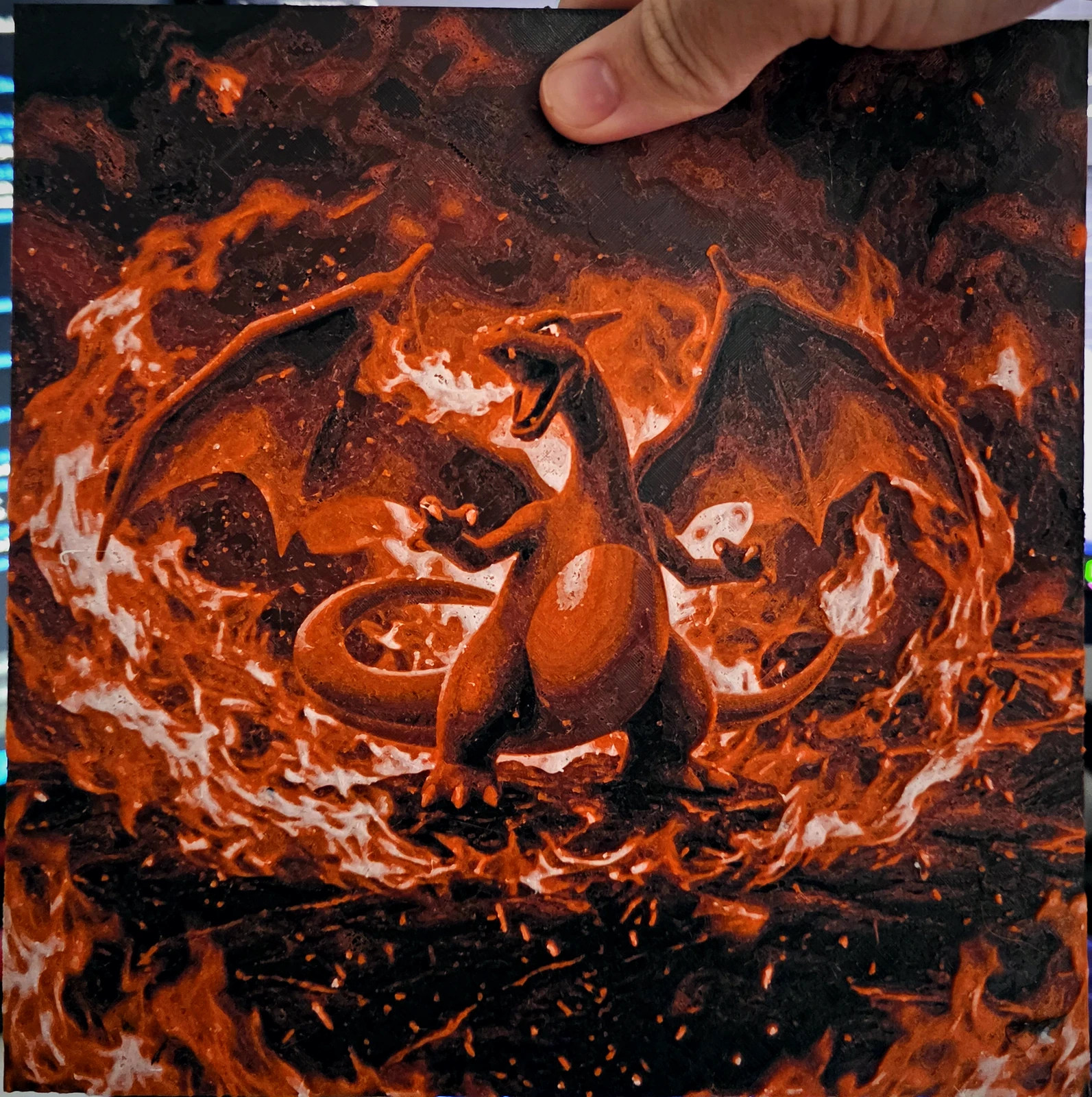Quadro do Charizard em tons de laranja e fogo, impresso em 3D, seguro pela mão